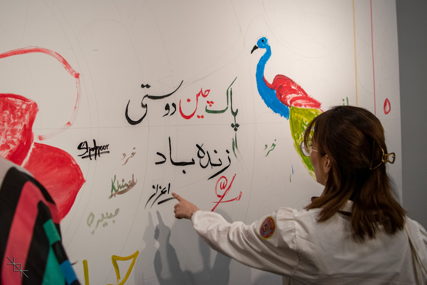 Attendees painting their names on the interactive art exhibit along side urdu tect which says "Long Live Pakistan China Friendship".